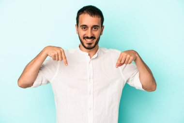 Kafkasyalı genç adam mavi arka planda izole edildi. Parmakları aşağıda, olumlu bir his var..