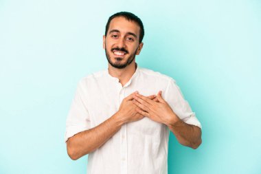 Mavi arka planda izole edilmiş beyaz bir genç, dost bir ifadeye sahip, avuçlarını göğsüne bastırıyor. Aşk konsepti.