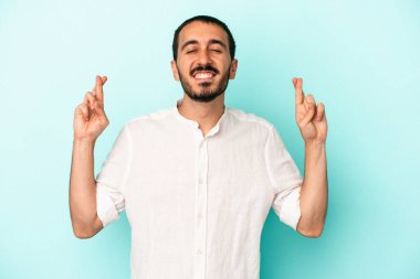 Kafkasyalı genç adam mavi arka planda izole edilmiş şans dilemek için şans diliyor.