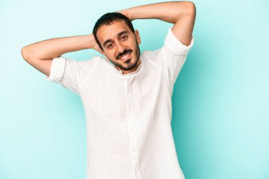 Mavi arka planda izole edilmiş genç beyaz adam kollarını uzatıyor, rahat bir konumda..