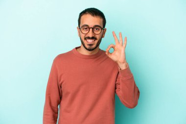 Kafkasyalı genç adam mavi arka planda izole edilmiş neşeli ve kendinden emin..