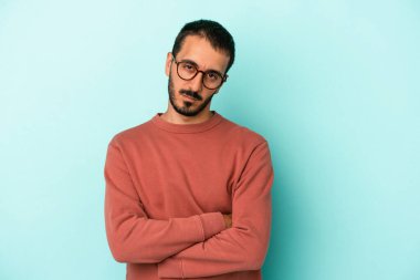 Kafkasyalı genç adam mavi arka planda izole edilmiş şüpheli, belirsiz, seni muayene ediyor..