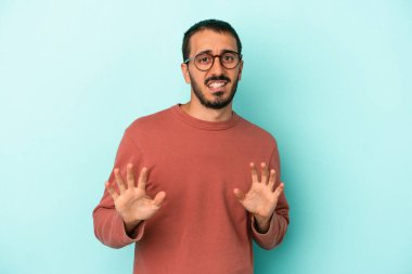 Mavi arka planda izole edilmiş genç beyaz adam tiksinti belirtisi gösteren birini reddediyor..