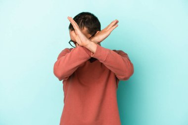 Kafkasyalı genç adam mavi arka planda izole edilmiş iki kolu çapraz tutuyor, inkar kavramı.