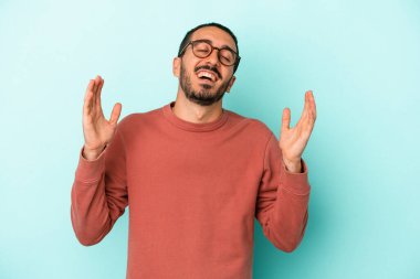 Kafkasyalı genç adam mavi arka planda izole edilmiş neşeli bir şekilde gülüyor. Mutluluk kavramı.
