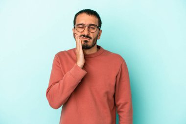 Mavi arka planda izole genç beyaz adam güçlü bir diş ağrısı, azıdişi ağrısı var..