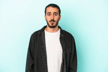 Kafkasyalı genç adam mavi arka planda izole edilmiş üzgün, ciddi yüzlü, mutsuz ve hoşnutsuz..
