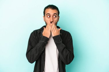 Kafkasyalı genç adam mavi arka planda izole edilmiş. Düşünceli bir şekilde ağzıyla ağzını kapatan bir fotokopi odasına bakıyor..