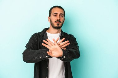 Mavi arka planda izole edilmiş genç beyaz adam elini uzatmış, dur işareti göstererek seni engelliyor..