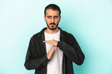 Mavi arka planda izole edilmiş genç beyaz bir adam bir mola hareketi gösteriyor..