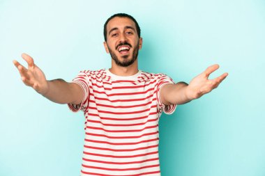 Mavi arka planda izole edilmiş genç beyaz adam kameraya sarıldığı için kendinden emin hissediyor..