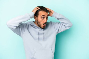 Genç beyaz adam mavi arka planda izole edilmiş bağırıyor, çok heyecanlı, tutkulu, bir şeyden memnun..