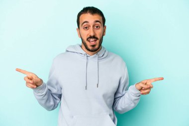 Mavi arka planda izole edilmiş genç beyaz adam farklı kopya alanlarını gösteriyor, birini seçiyor, parmaklarıyla gösteriyor.