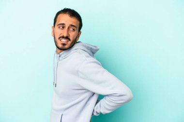 Mavi arka planda izole edilmiş beyaz bir adam sırt ağrısı çekiyor..