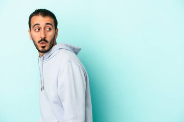 Mavi arka planda soyutlanmış genç beyaz bir adam gülümsüyor, neşeli ve keyifli görünüyor..