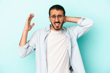 Mavi arka planda izole edilmiş genç beyaz adam öfkeyle bağırıyor..