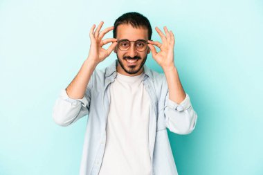 Kafkasyalı genç adam mavi arka planda izole edildi. Heyecanlı görünüyor..