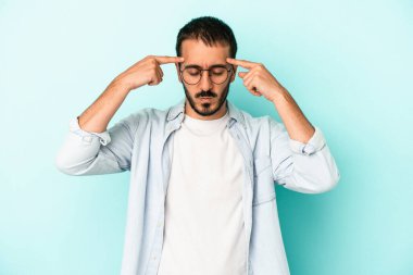 Kafkasyalı genç adam mavi arka planda izole edilmiş bir göreve odaklanmış, parmaklarını işaret ediyor..