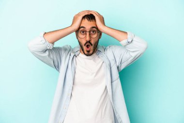 Kafkasyalı genç adam mavi arka planda izole edildi. Şaşırdı ve şok oldu..