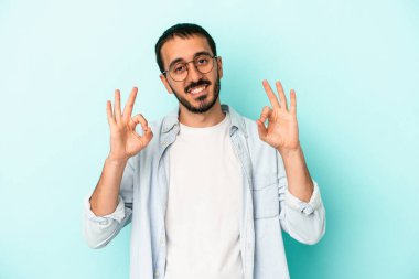 Kafkasyalı genç adam mavi arka planda izole edilmiş neşeli ve kendinden emin..