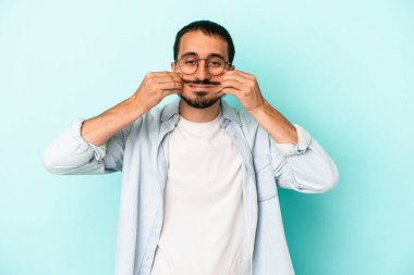 Kafkasyalı genç adam mavi arka planda izole edilmiş iki seçenek arasında şüphe duyuyor.