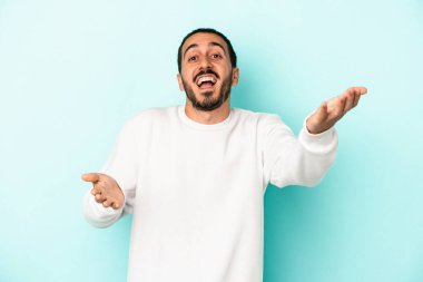 Mavi arka planda izole edilmiş genç beyaz adam kameraya sarıldığı için kendinden emin hissediyor..
