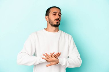 Kafkasyalı genç adam mavi arka planda izole edilmiş bir şekilde inkar hareketi yapıyor.