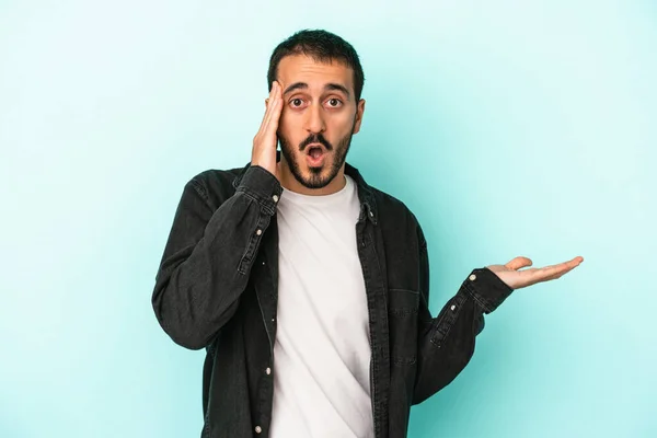 Young Caucasian Man Isolated Blue Background Impressed Holding Copy Space — Stock Photo, Image