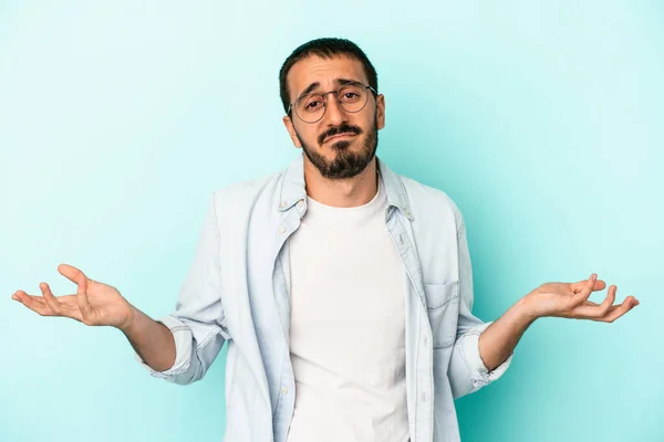 Joven Hombre Caucásico Aislado Sobre Fondo Azul Dudando Encogiéndose Hombros — Foto de Stock