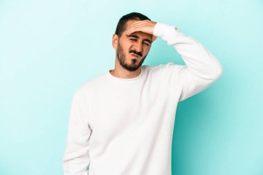 Genç beyaz adam mavi arka planda izole edilmiş tapınaklara dokunuyor ve başı ağrıyor..