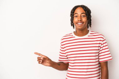 Beyaz arka planda izole edilmiş genç bir Afrikalı Amerikalı işaret parmağıyla işaret ederek gülümsüyor..