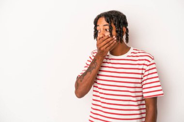 Genç Afrikalı Amerikalı bir adam beyaz arka planda izole edilmiş. Düşünceli bir şekilde bir fotokopi odasına bakıyor. Ağzını eliyle kapatıyor..