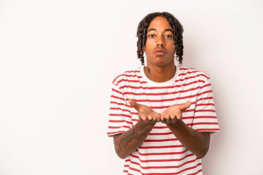 Beyaz arka planda izole edilmiş genç Afrikalı Amerikalı dudaklarını kıvırıyor ve hava öpücüğü yollamak için avuç içleri tutuyor..