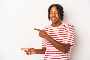 Beyaz arka planda izole edilmiş genç Afrikalı Amerikalı adam işaret parmağıyla fotokopi alanını işaret ederek şok oldu..