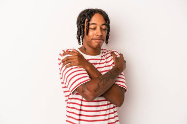 Genç Afrikalı Amerikalı adam beyaz arka plan kucaklamalarında yalnız, kaygısız ve mutlu bir şekilde gülümsedi..