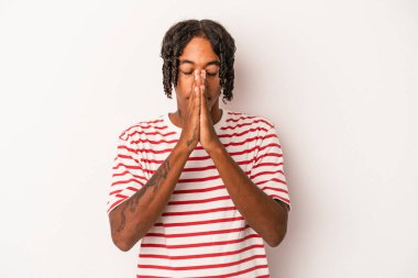 Beyaz arka planda izole edilmiş genç Afro-Amerikan bir adam el ele tutuşup dua ederken kendine güveniyor..