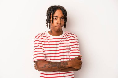 Beyaz arka planda izole edilmiş, hoşnutsuzca kaşlarını çatmış, kollarını kavuşturmuş genç Afrikalı Amerikalı bir adam..
