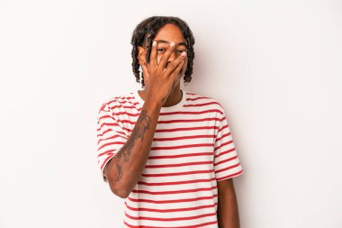 Genç Afrikalı Amerikalı adam beyaz arka planda izole edilmiş. Kameraya parmaklarıyla göz kırpıyor. Yüzünü kapatmaktan utanıyor..