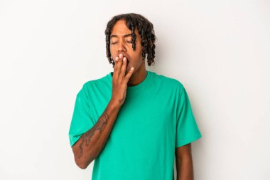 Beyaz arka planda izole edilmiş genç Afrikalı Amerikalı adam esniyor. Ağzını eliyle kapatan yorgun bir hareket sergiliyor..