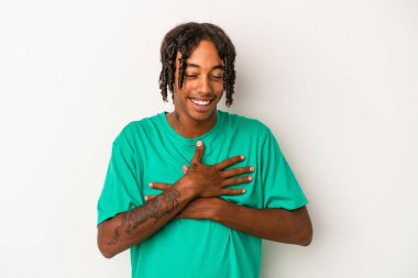 Beyaz arka planda izole edilmiş genç Afrikalı Amerikalı adam mutlu bir şekilde gülüyor ve ellerini karnının üstünde tutarak eğleniyor..