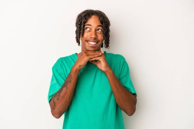 Beyaz arka planda izole edilmiş genç Afrikalı Amerikalı ellerini çenesinin altında tutuyor ve mutlu bir şekilde yan tarafa bakıyor..