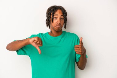 Beyaz arka planda izole edilmiş genç Afro-Amerikalı adam baş parmağını kaldırıyor ve baş parmağını aşağı gösteriyor, zor seçim konsepti