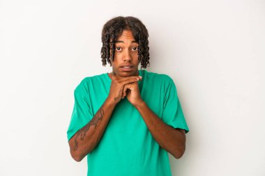 Genç Afro-Amerikalı adam beyaz arka planda izole edilmiş şans için dua ediyor, şaşırmış ve ağzını açıyor..