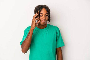 Genç Afrikalı Amerikalı adam beyaz arka planda izole edilmiş, parmakları dudaklarında bir sır saklıyor..