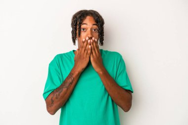 Beyaz arka planda izole edilmiş genç Afrikalı Amerikalı adam şok olmuş, ağzı ellerle kaplanmış, yeni bir şey keşfetmeye hevesli..