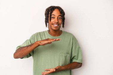 Beyaz arka planda izole edilmiş genç Afrikalı Amerikalı iki eliyle bir şey tutuyor, ürün sunumu..