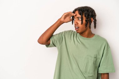 Genç Afrikalı Amerikalı adam beyaz arka planda izole edilmiş, uzaklara bakıyor ve elini alnına koyuyor..