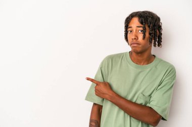 Beyaz arka planda izole edilmiş genç Afrikalı Amerikalı adam gülümsüyor ve boş alanda bir şeyler gösteriyor..