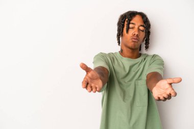 Beyaz arka planda izole edilmiş genç Afrikalı Amerikalı dudaklarını kıvırıyor ve hava öpücüğü yollamak için avuç içleri tutuyor..