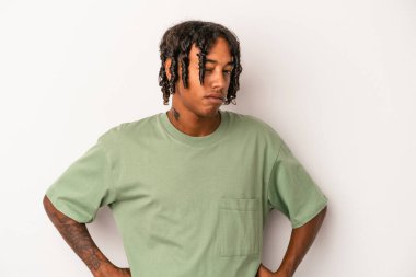 Beyaz arka planda izole edilmiş, hoşnutsuzca kaşlarını çatmış, kollarını kavuşturmuş genç Afrikalı Amerikalı bir adam..